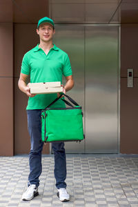 Full length portrait of smiling man standing against the wall