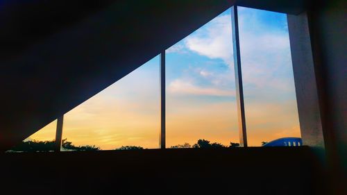 Silhouette trees against sky seen through window during sunset