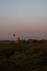 Sunrise in bagan. hot air balloon flying next to a pagoda.