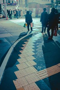 Rear view of people walking on footpath in city