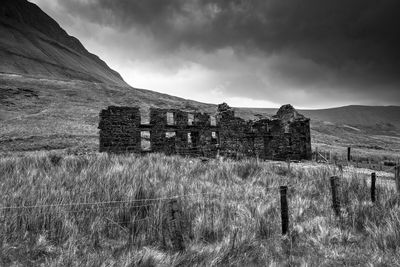 Old ruins on grassy field against cloudy sky