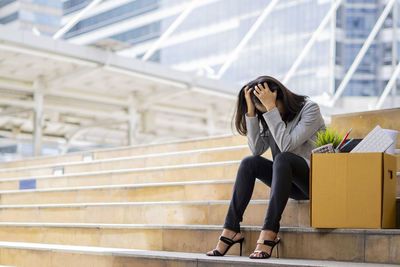 Full length of woman sitting on staircase