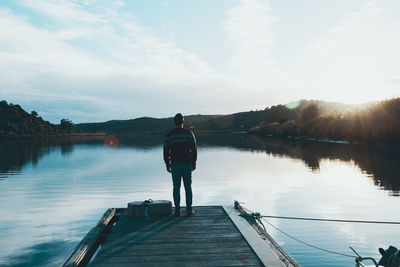 Rear view of man standing on jetty over lake