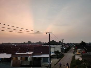 Street and houses against sky during sunset