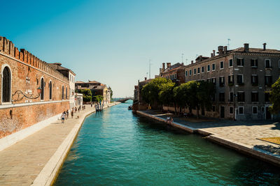 Canal amidst buildings against clear sky