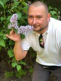 Portrait of man smelling purple flower