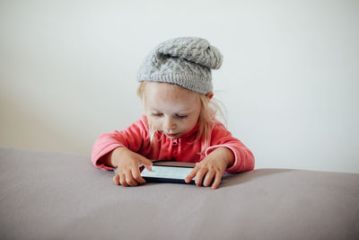 Cute girl holding mobile phone at home