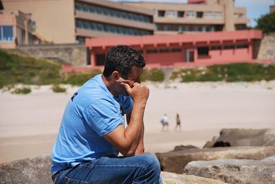 Man photographing while sitting outdoors