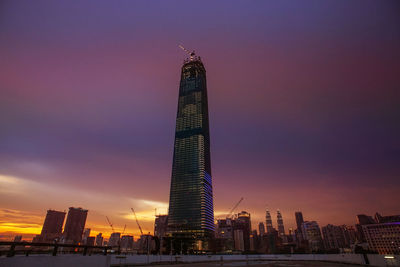Illuminated buildings in city against sky during sunset