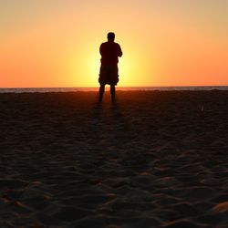 Silhouette man standing on beach during sunset