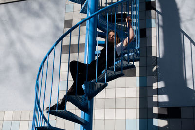 Low angle view of woman sitting on spiral staircase