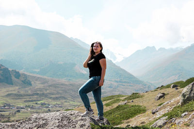 Portrait of woman standing on rock against mountain range
