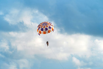 Low angle view of person paragliding against sky