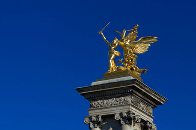 Low angle view of gold statue against clear blue sky at pont alexandre iii