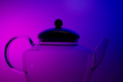 Close-up of glass kettle against colored background