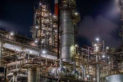 Low angle view of illuminated factory against sky at night