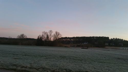 Scenic view of snowy field against sky during sunset