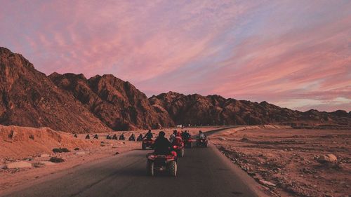 Rear view of people riding motorcycle on road against sky