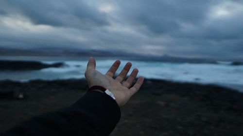 Close-up of hand against sea