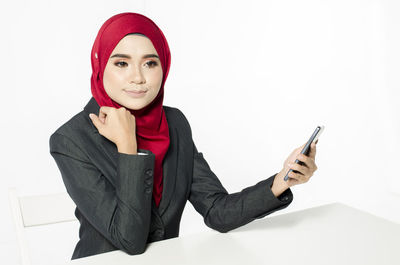 Portrait of young woman wearing mask against white background