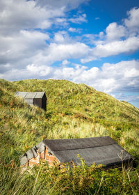 Huts on hill against cloudy sky