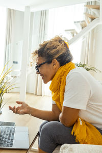 Side view of man using laptop while sitting at home