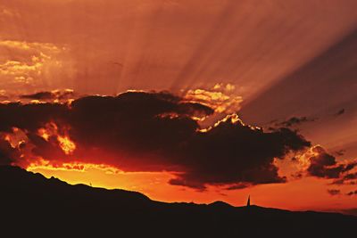 Silhouette mountain against dramatic sky during sunset