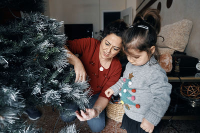 Grandparents decorate the christmas tree with their little granddaughter