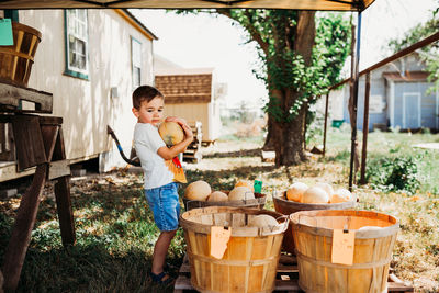 Young boy outside holding fresh cantaloupe at local farmers market
