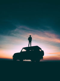 Silhouette man standing by car against sky during sunset