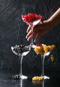 Cropped hand of woman stacking wineglasses with various currants