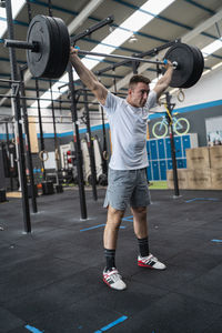 Confident sportsman holding barbell with weights in gym