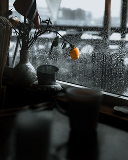 Close-up of wet glass on table against window during rainy season