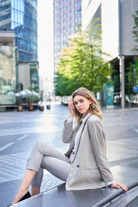 Portrait of young woman sitting in city