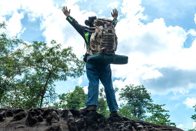 Low angle view of man standing on rock against sky