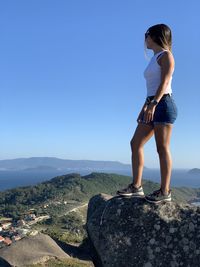 Full length of woman standing on rock against sky