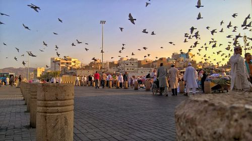 People at town square against clear sky during sunset