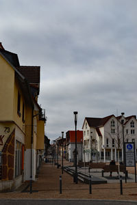 Houses by street in city against sky
