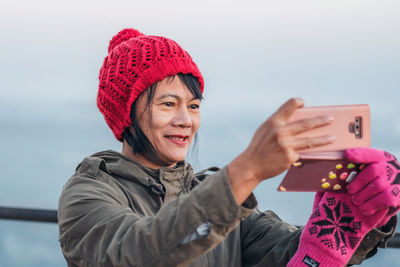 Portrait of smiling woman holding smart phone during winter