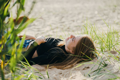 Side view of woman lying on sand at beach