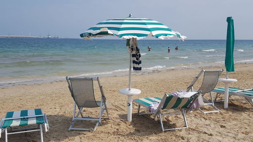 Deck chairs on beach against clear sky