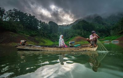 Woman sitting with fisherman on rowboat