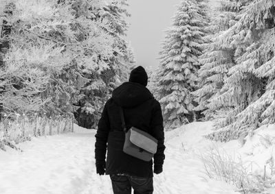 Rear view of man on snow covered trees
