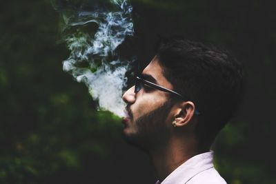 Side view of young man smoking outdoors