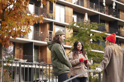 Side view of smiling couple standing against building