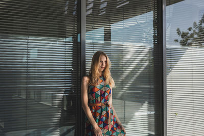 Woman looking away while standing against wall