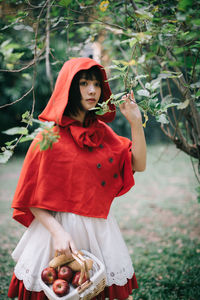 Young woman holding red while standing on land