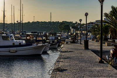 Sailboats moored at harbor during sunset