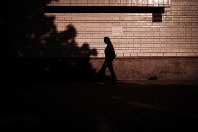 Silhouette man walking on footpath by street