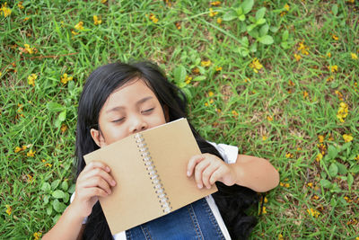 High angle view of girl with book sleeping on grassy field at park